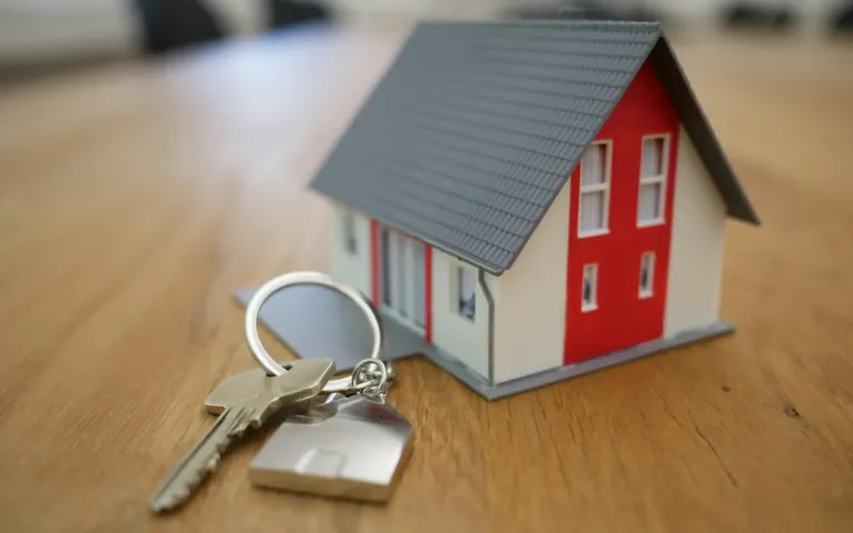 Model house with a house key on a wooden table